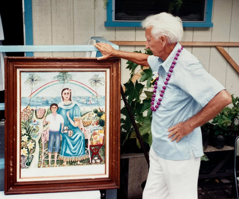 Fritz Sydow holding a framed artwork of a religious scene with a rainbow and palm trees he painted